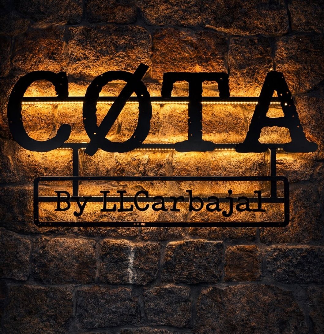Letrero de CØTA by LLCarbajal retroiluminado sobre la pared de piedra