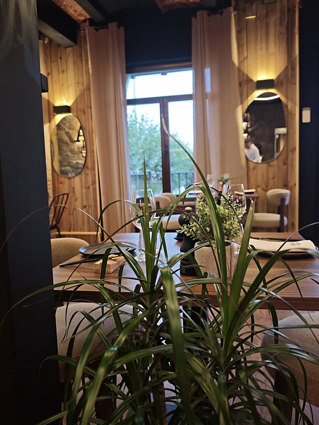 Comedor de CØTA con cortinas de lino, madera y plantas